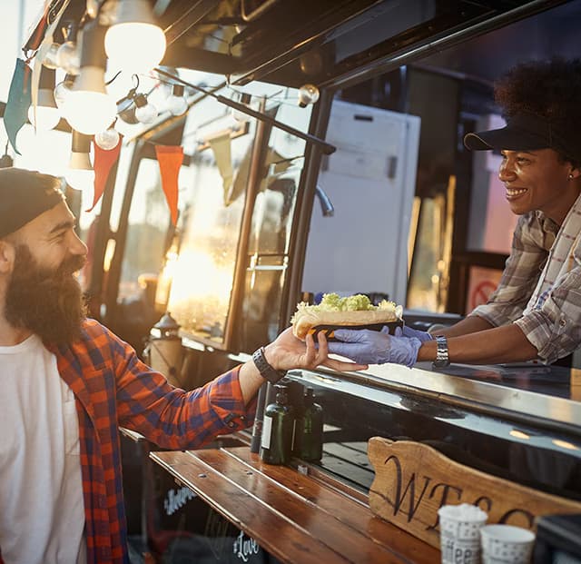 A woman handing a man food out of a food truck