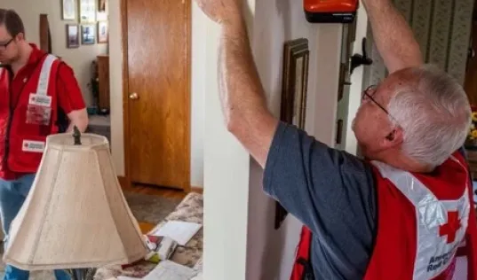 red cross volunteer drilling into a wall