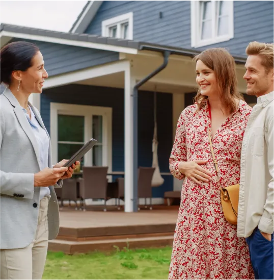 couple with agent in front of home