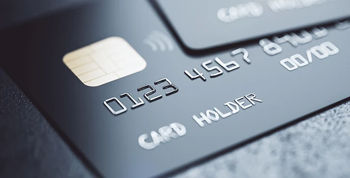 The bottom left corner of a grey credit card on a lighter background, with the bottom right corner of another card above it